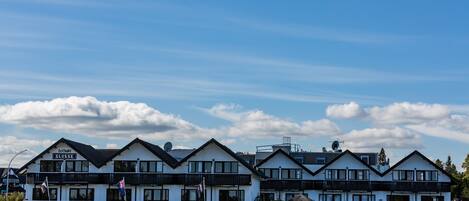 A row of white buildings with black trim and multiple balconies, under a clear sky.