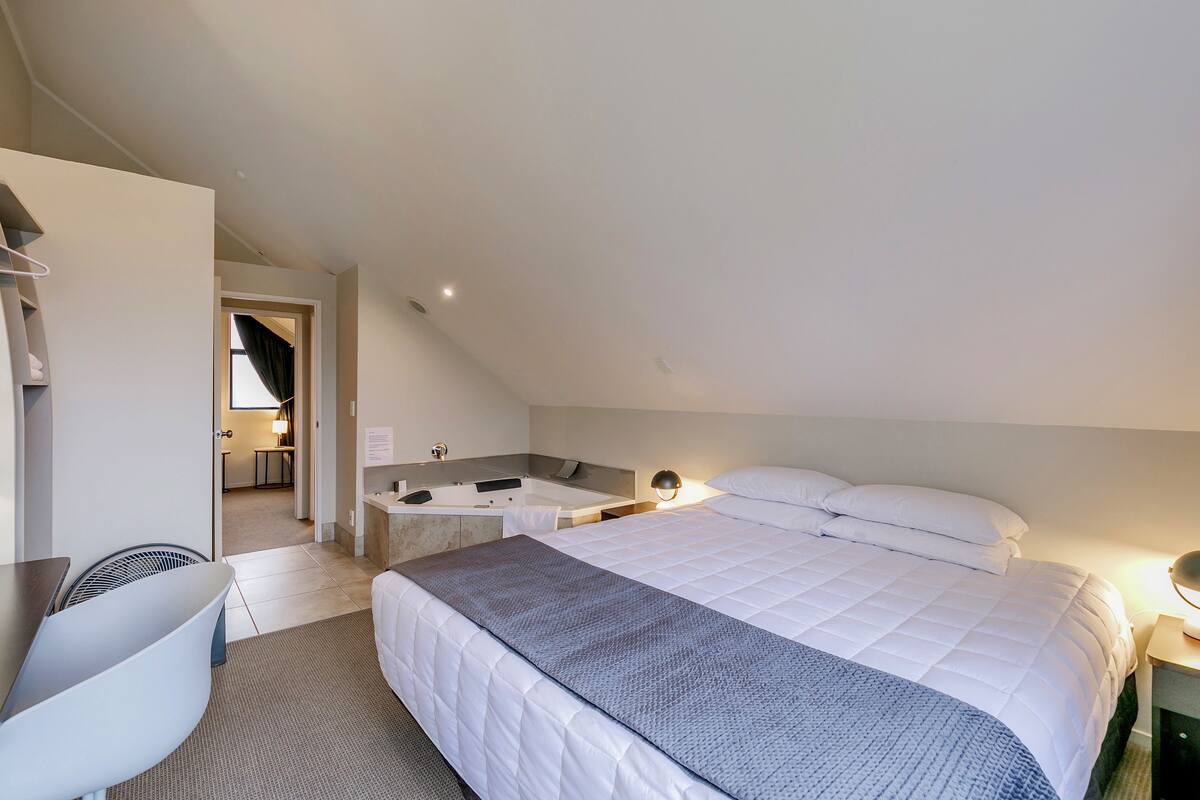Une chambre d’hôtel moderne dotée d’un grand lit, d’un bureau et d’une salle de bain séparée.