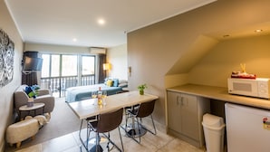 Une chambre d’hôtel compacte dotée d’un balcon, d’un coin repas, d’une kitchenette et d’une petite poubelle.