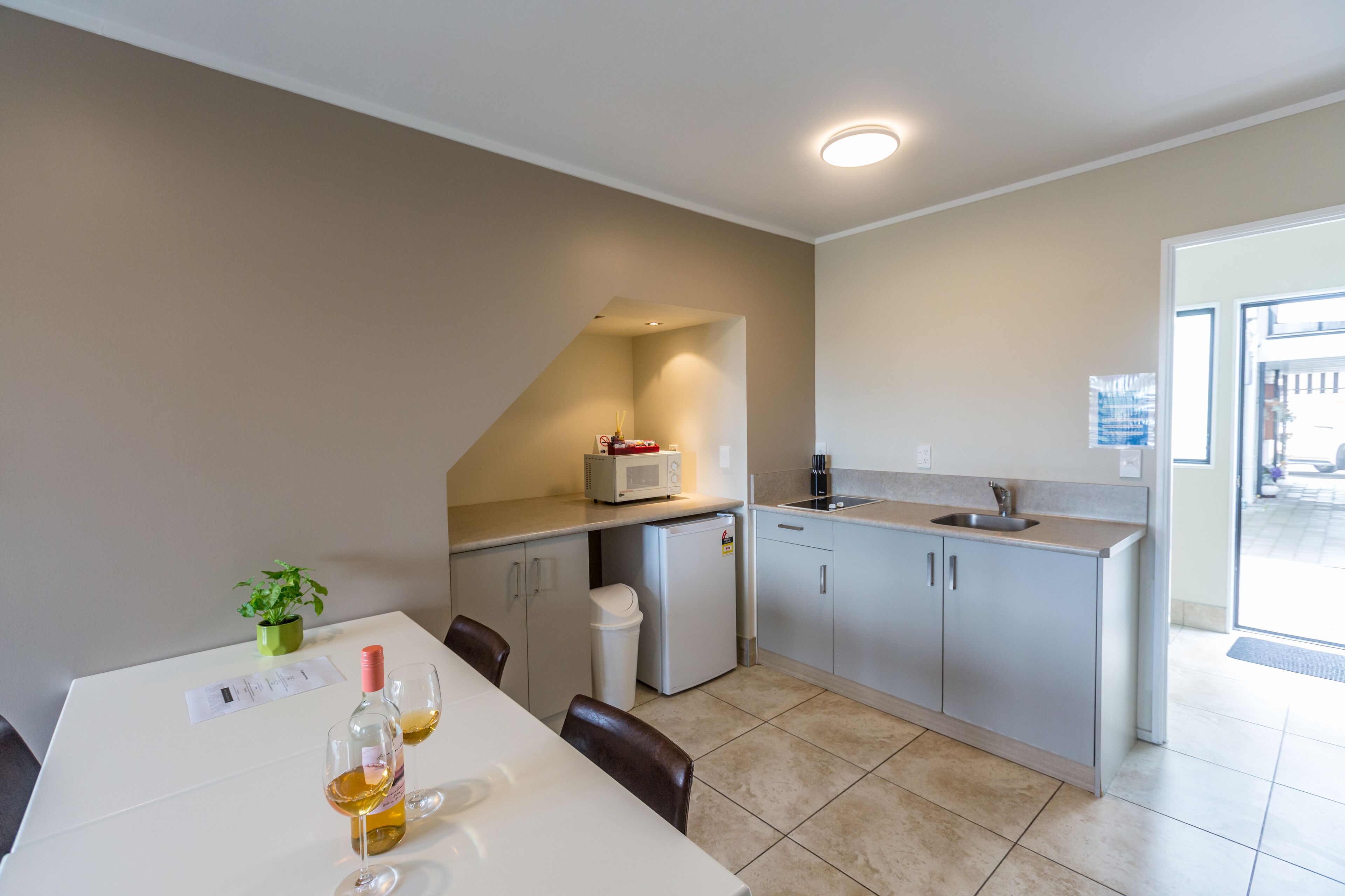 Eine moderne Küche mit Essbereich, ausgestattet mit einem weißen Tisch, Stühlen, einem kleinen Kühlschrank und einer Mikrowelle.