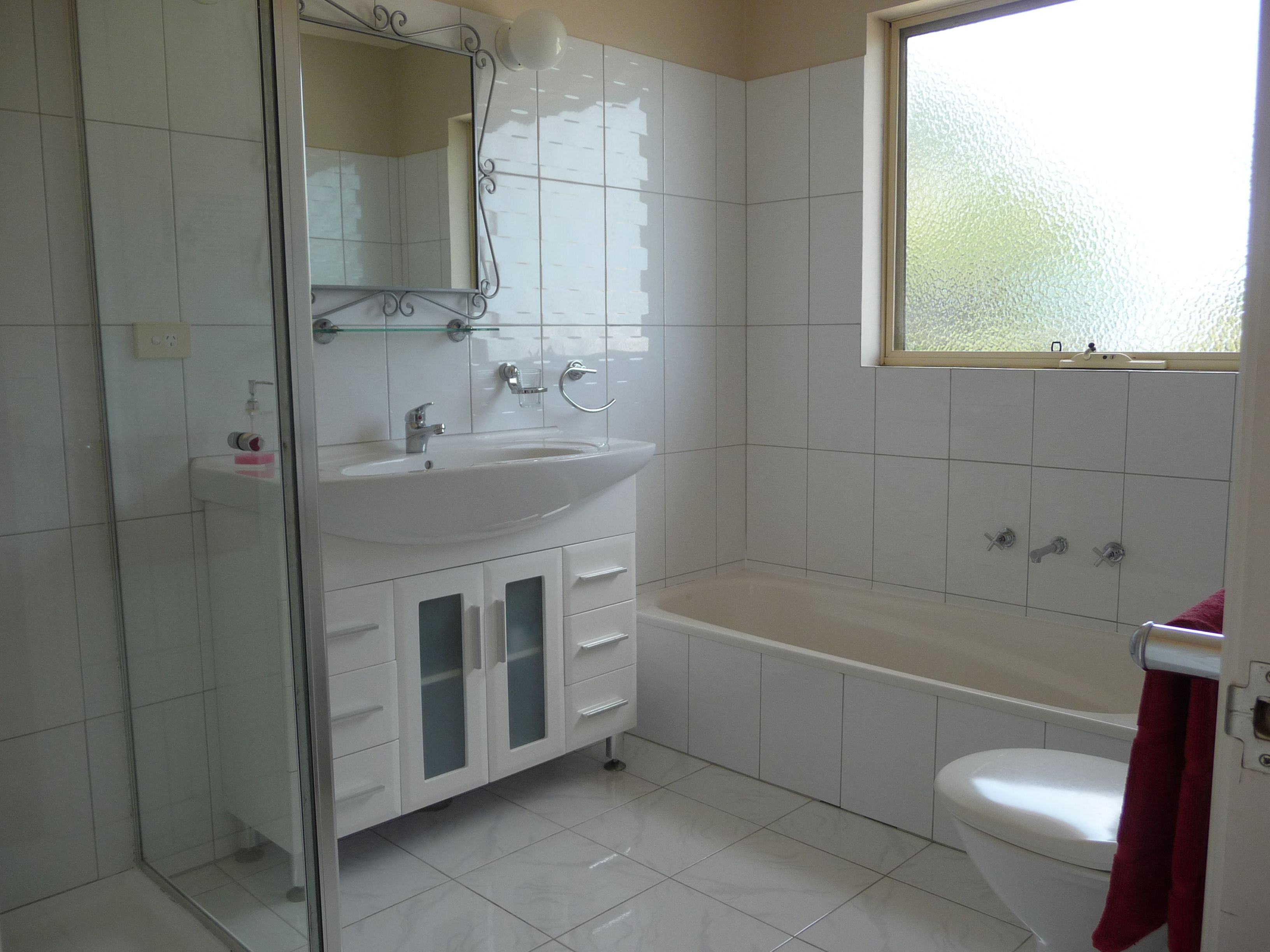 Un baño con lavamanos, espejo y bañera blancos.