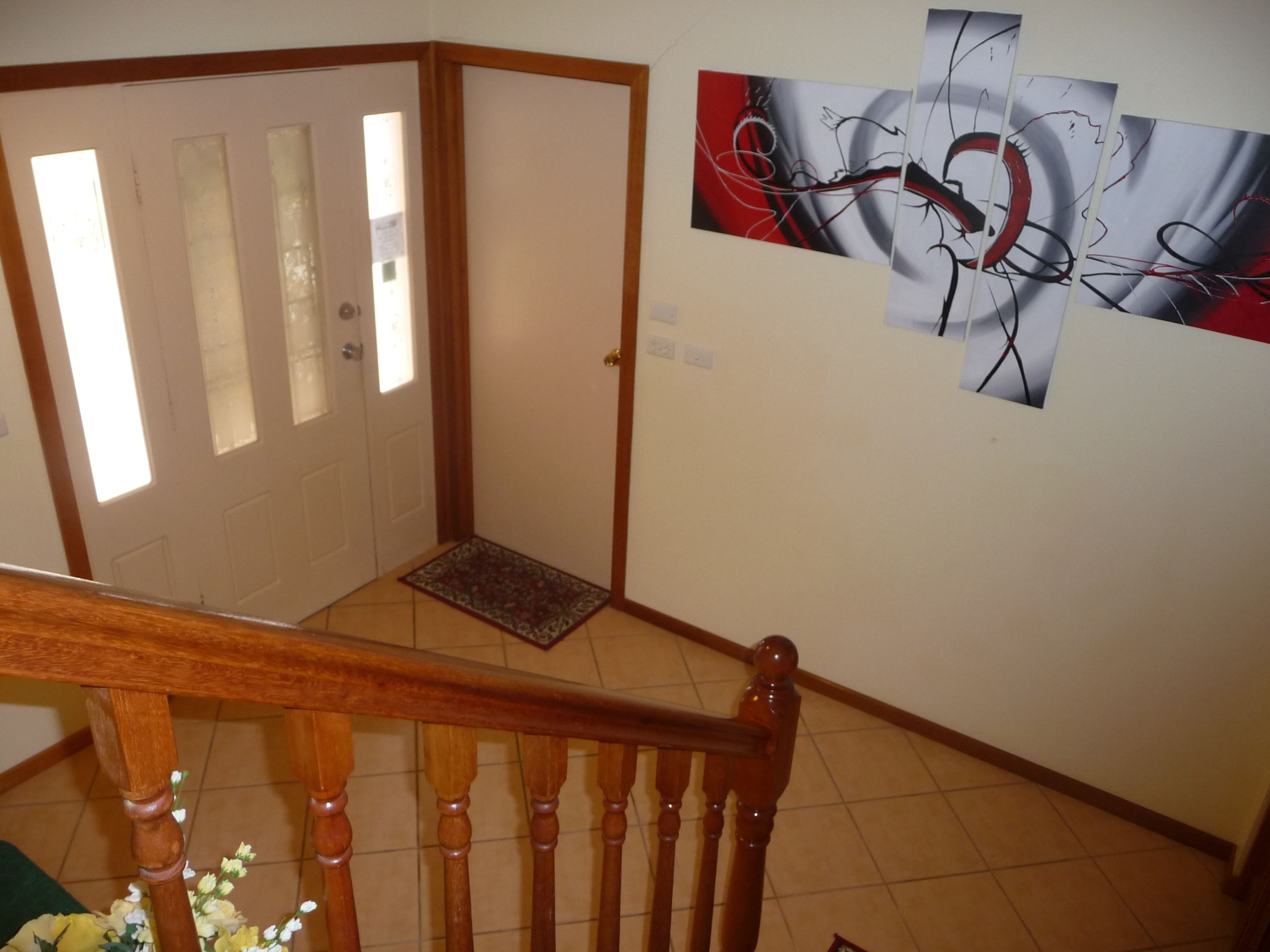 A staircase with wooden balusters and a handrail, leading to a landing with a doormat and a door with frosted glass panels.
