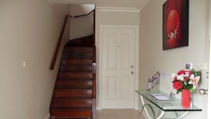 A staircase leading to a private door, a glass table with a vase of flowers, and a framed picture on the wall. - Angela's Beach Stays (Apollo Bay)