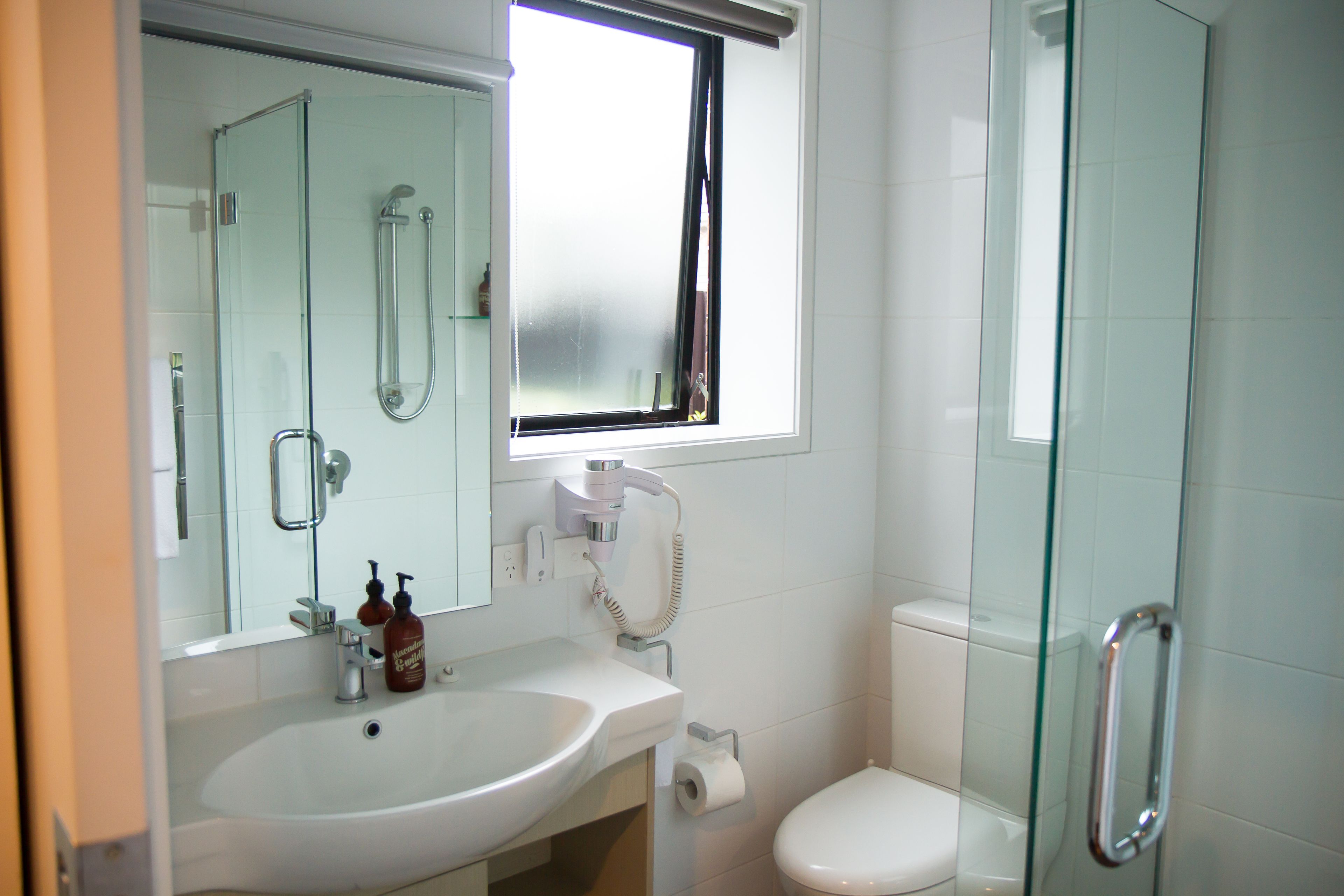 Un baño con cabina de ducha de vidrio, un lavabo blanco y un inodoro.