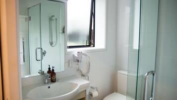 Un baño con cabina de ducha de vidrio, un lavabo blanco y un inodoro.