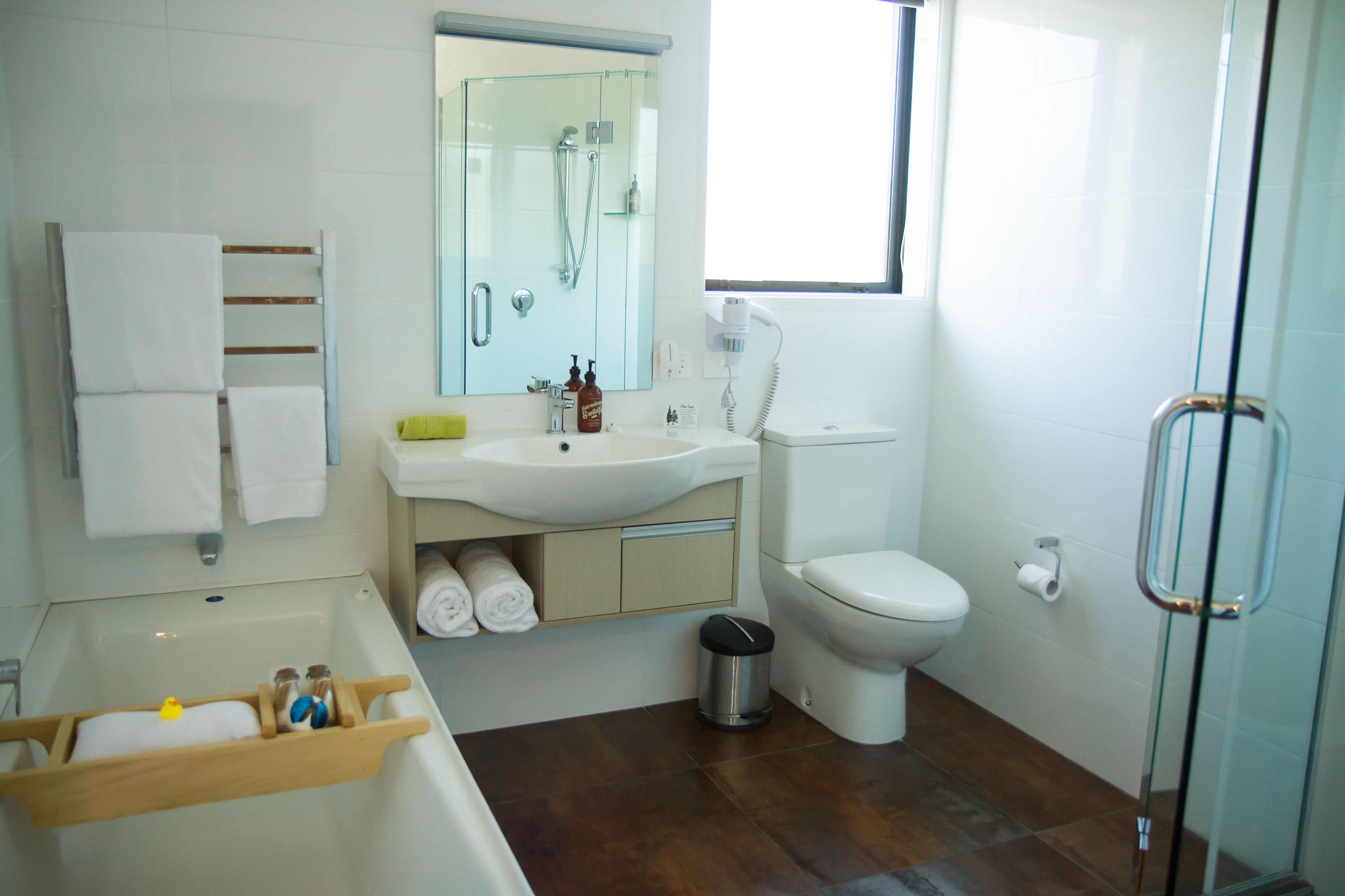A modern bathroom with a bathtub, sink, toilet, and glass shower enclosure.