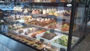A bakery display case with various pastries and desserts. - 850 Cameron Motel (Tauranga)