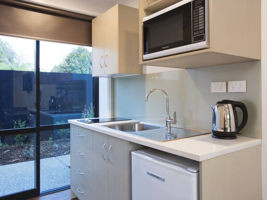 A modern kitchen with a stainless steel sink, a microwave, and a kettle on the countertop.