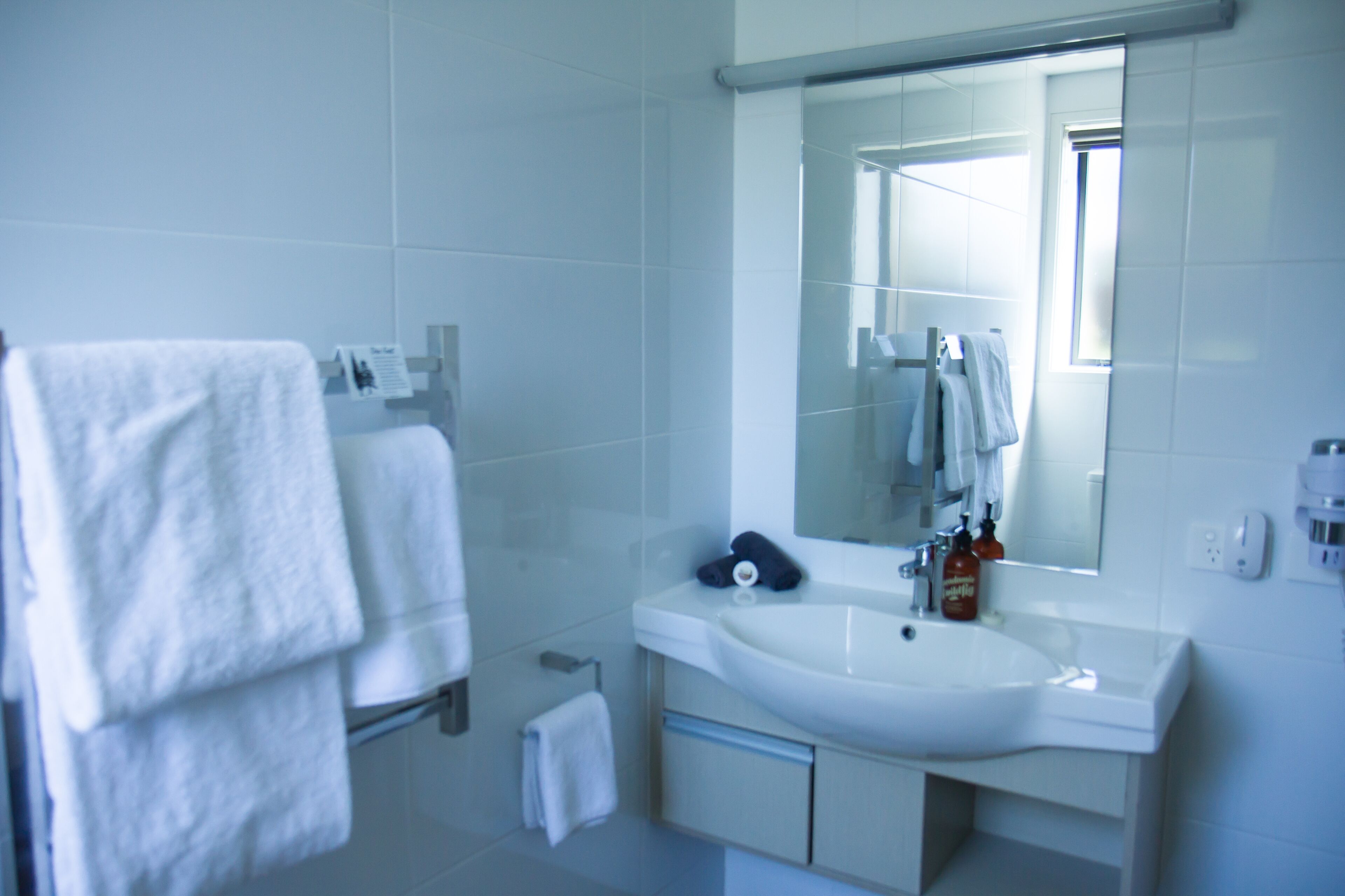 A modern bathroom with a white sink, mirror, and towel rack.