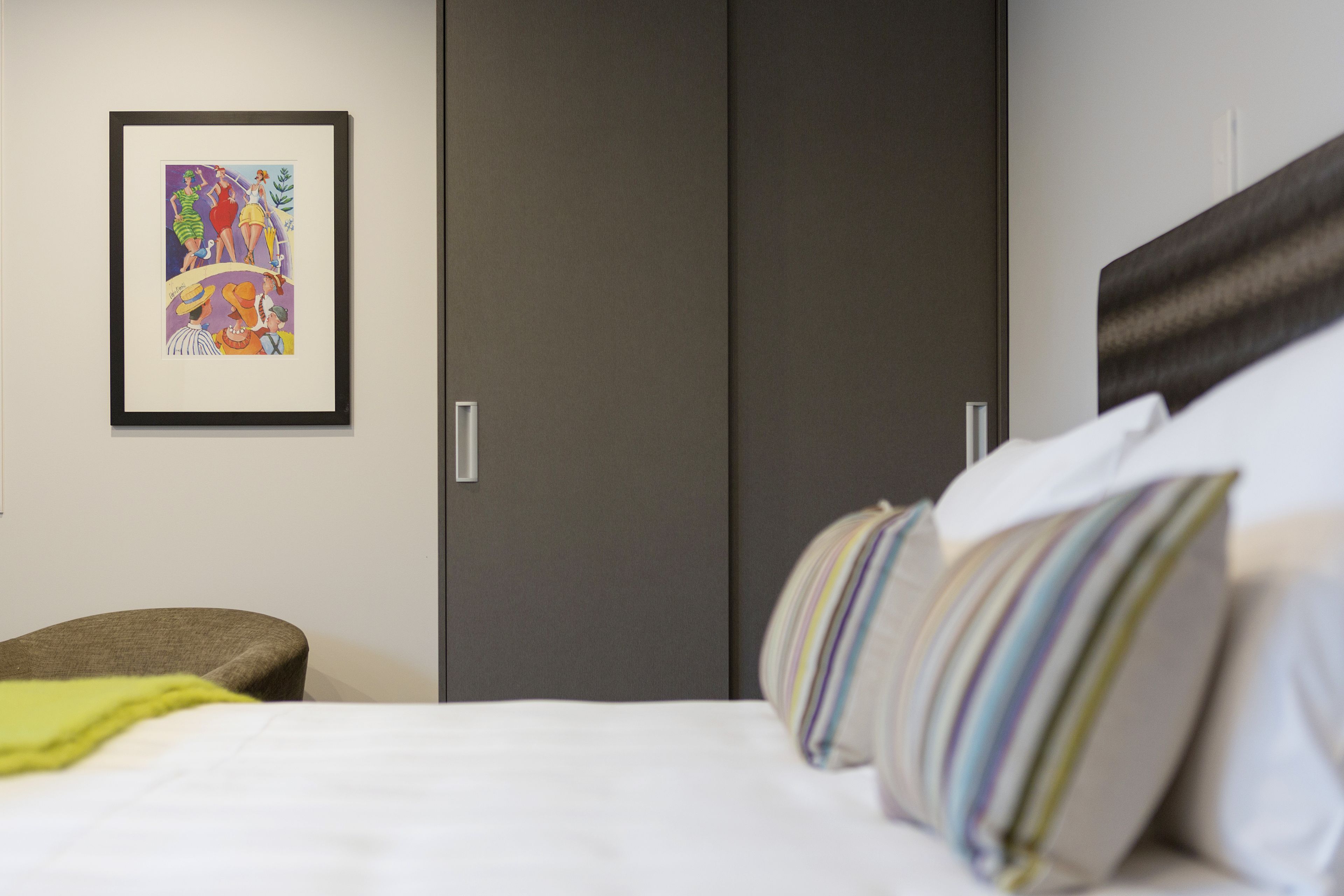 Una habitación de hotel con una cama, un cuadro en la pared y un armario.