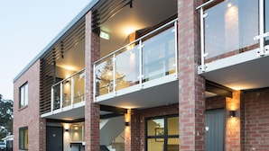 A modern building with a brick facade, a covered outdoor area with glass railings, and a staircase leading to an upper level. - 850 Cameron Motel (Tauranga)