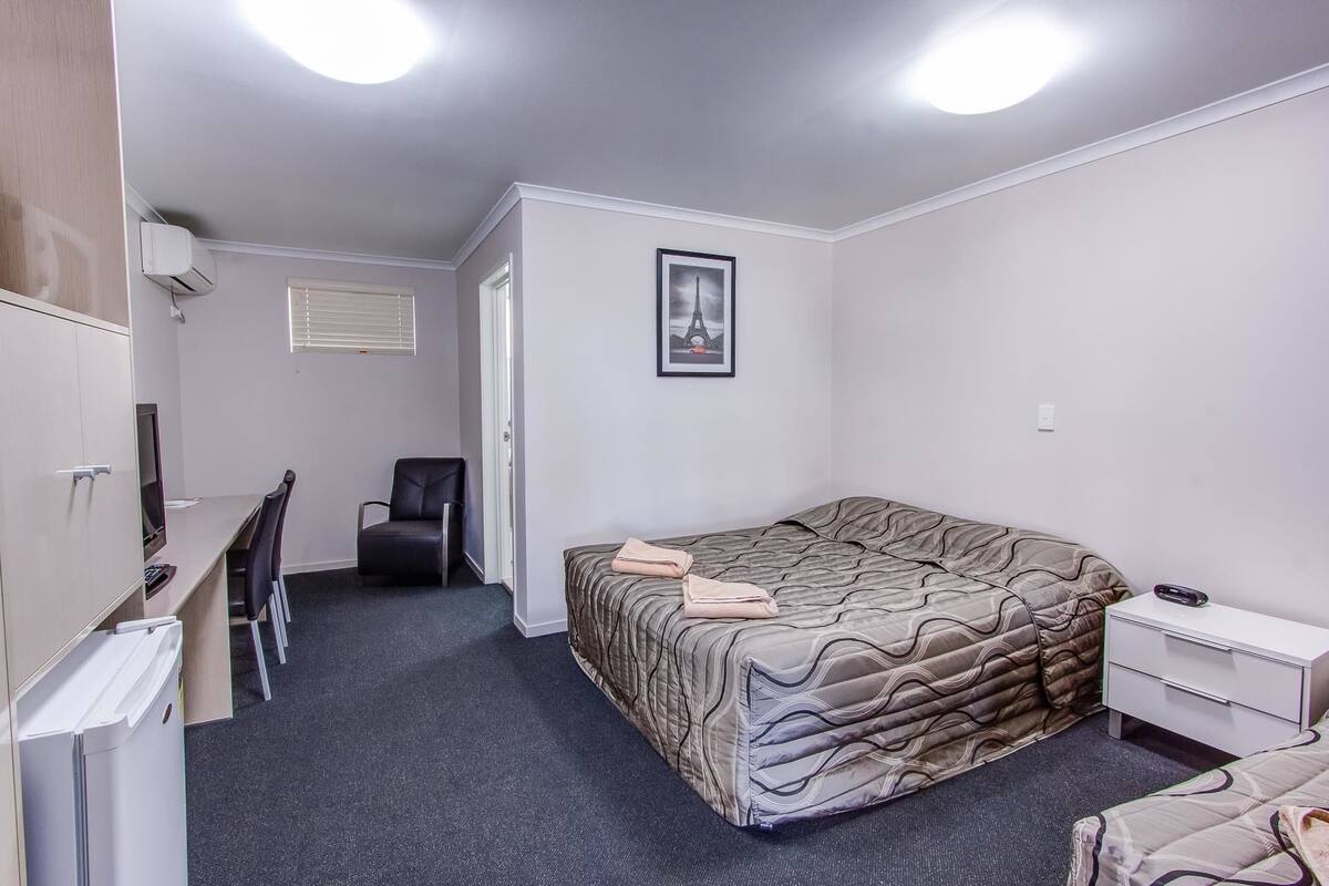 A compact bedroom with a bed, a desk, a chair, and a wardrobe.