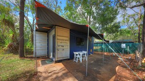 A small, enclosed outdoor area with a table and chairs, surrounded by trees and a covered structure. - Batchelor Holiday Park (Batchelor)