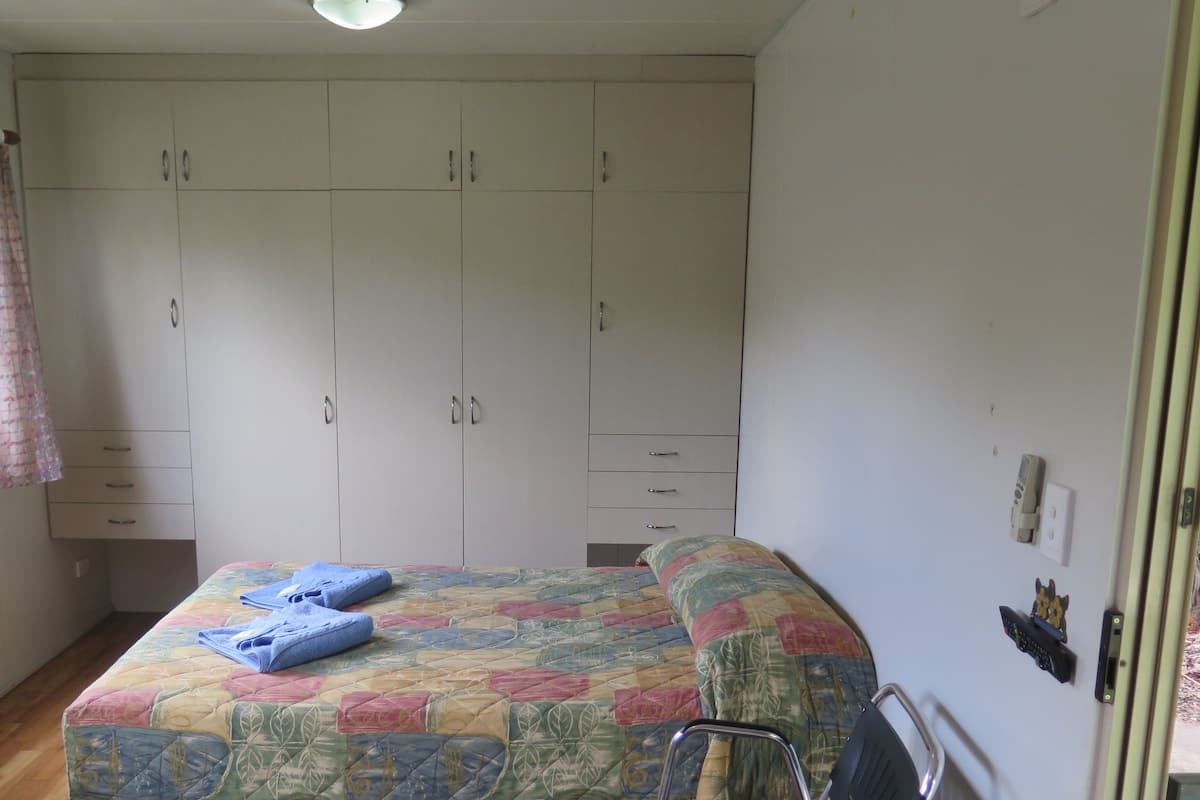 A bedroom with a bed, a wardrobe, and a window with curtains.