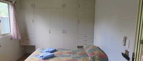 Une chambre à coucher avec un lit, une armoire et une fenêtre avec des rideaux.
