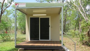 A small, single-story structure with a covered porch and a sliding glass door. - Batchelor Holiday Park (Batchelor)