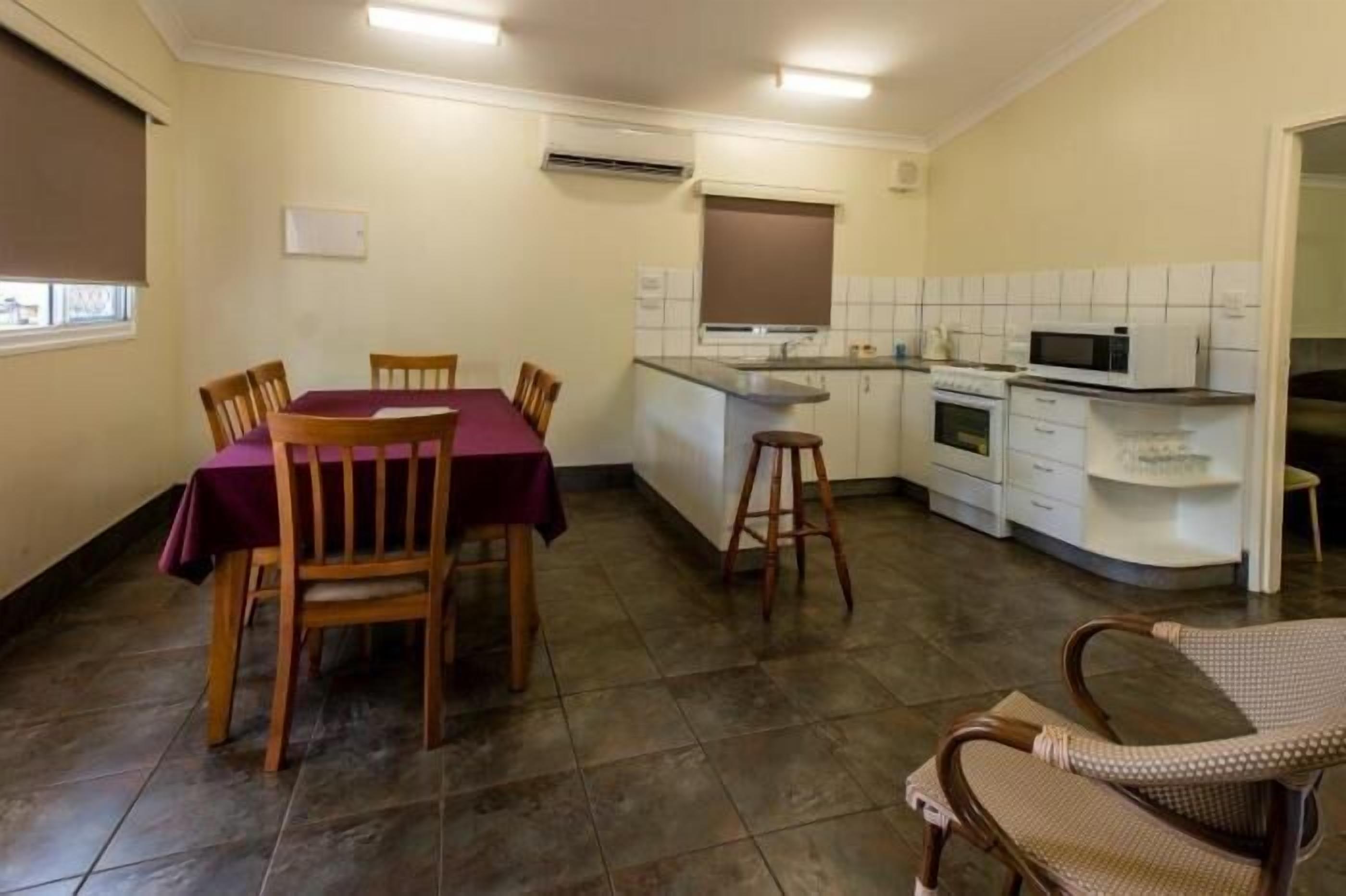 Une cuisine compacte comprenant une table et des chaises, un four à micro-ondes et un petit îlot central.