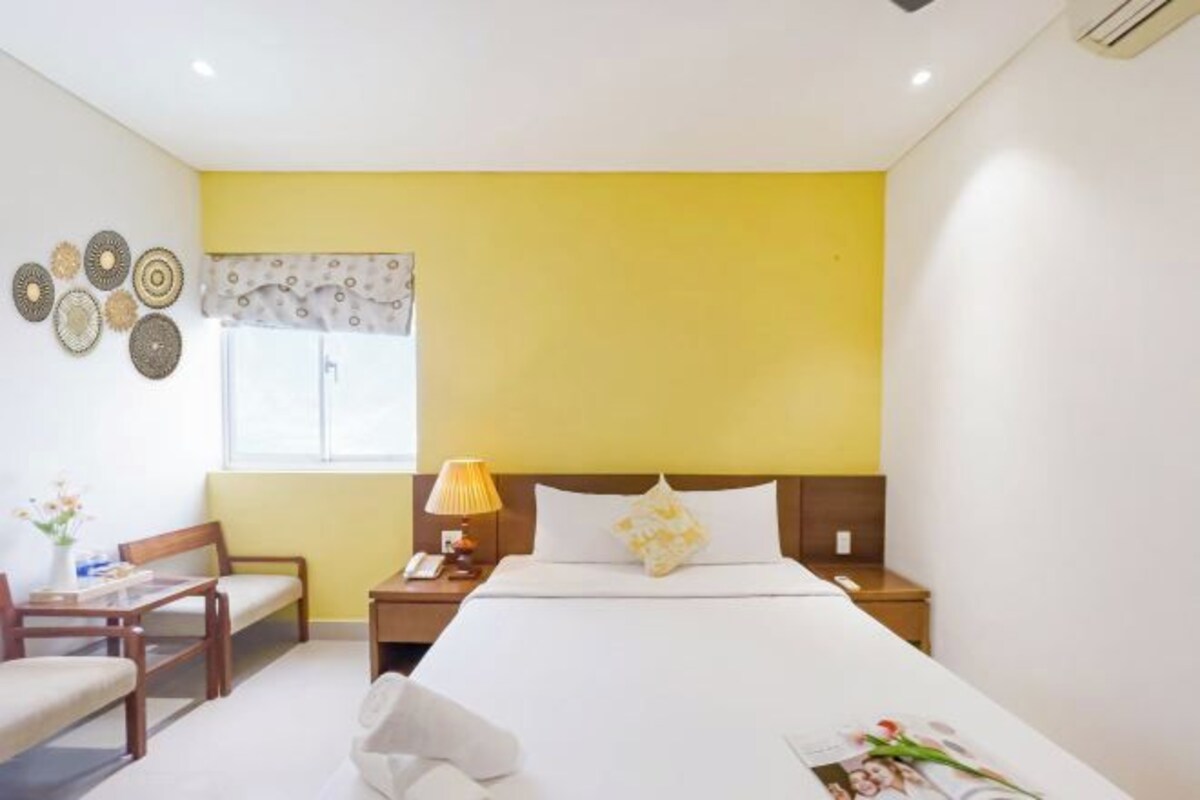 A hotel room with a bed, bedside tables, a chair, a lamp, and decorative wall art.