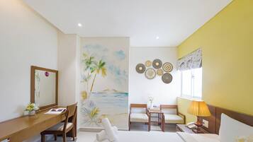 Una habitación de hotel con una cama, dos sillas, un escritorio, un espejo, una pared decorada con platos y una ventana con cortinas.