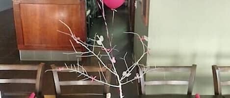 Un interior de restaurante con mesas y sillas de madera, un mostrador de recepción y globos.