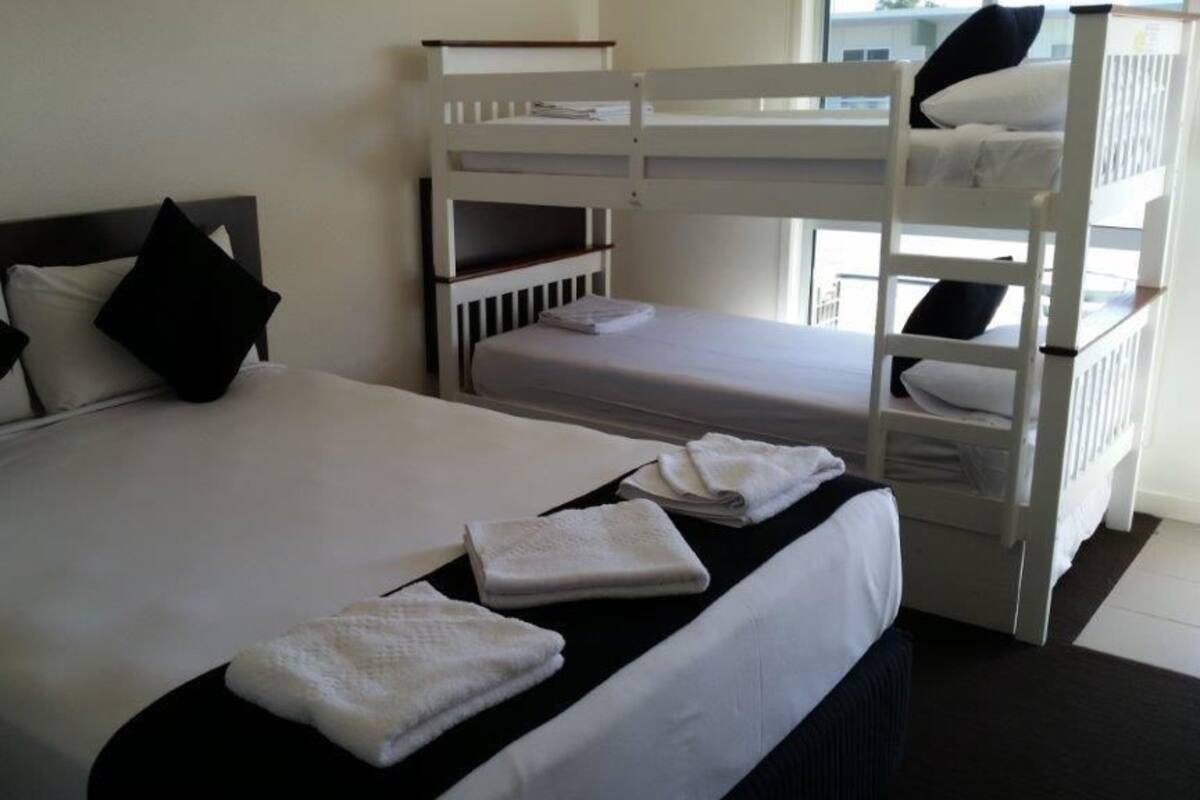 Une chambre d’hôtel avec un lit simple, un lit superposé et une fenêtre donnant sur un paysage.
