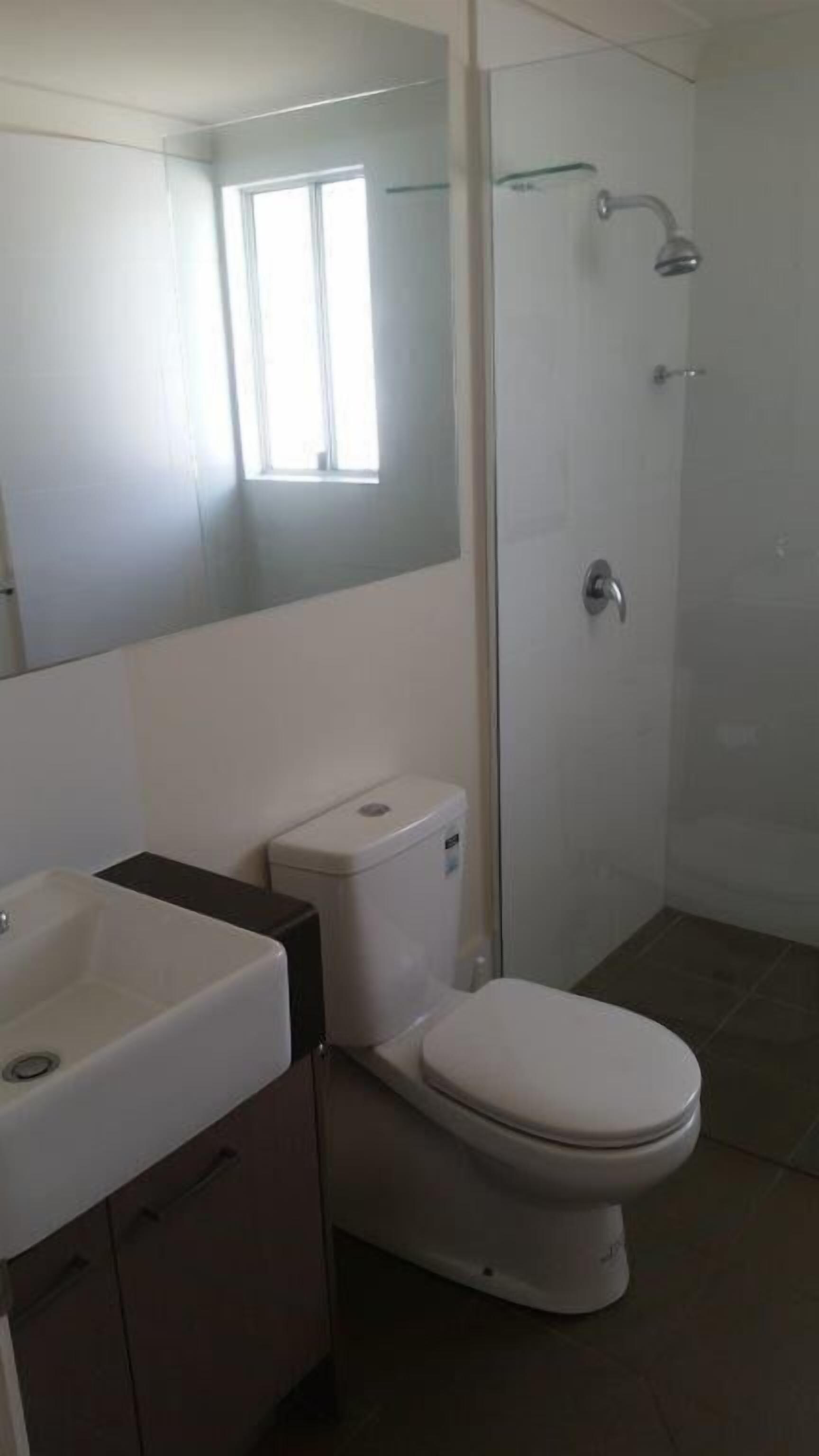 Casa de banho com sanita, lavatório e chuveiro.