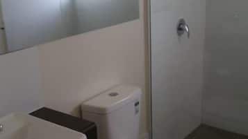 Casa de banho com sanita, lavatório e chuveiro.