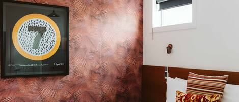 Une chambre d’hôtel avec un lit, une chaise, une œuvre d’art encadrée au mur et une fenêtre.