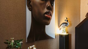 A modern interior with a large framed artwork, a decorative bird sculpture, and a potted plant on a console table. - The State Hotel (New Plymouth)