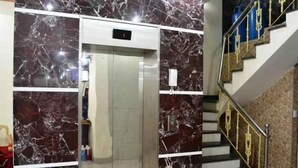 An elevator with marble walls, a staircase with golden railings, and a red carpet leading to the stairs. - My Ngoc Hotel Catba (Hai Phong)
