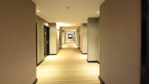 Un pasillo de hotel con piso alfombrado, puertas a ambos lados e iluminación empotrada.