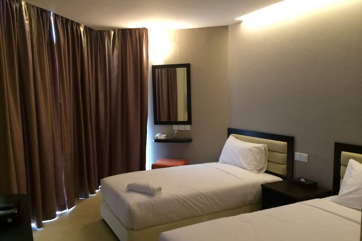 A hotel room with two beds, a bedside table, a nightstand, a mirror, a telephone, and a curtain.