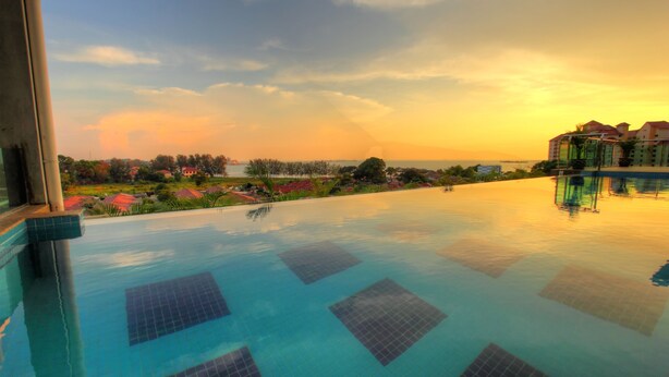 Una piscina con vista a un edificio turístico y un paisaje lejano.