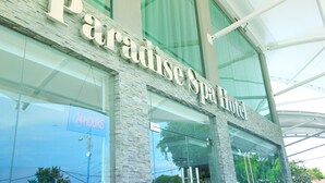 Exterior del Paradise Spa Hotel, con una amplia fachada de vidrio y un letrero llamativo.