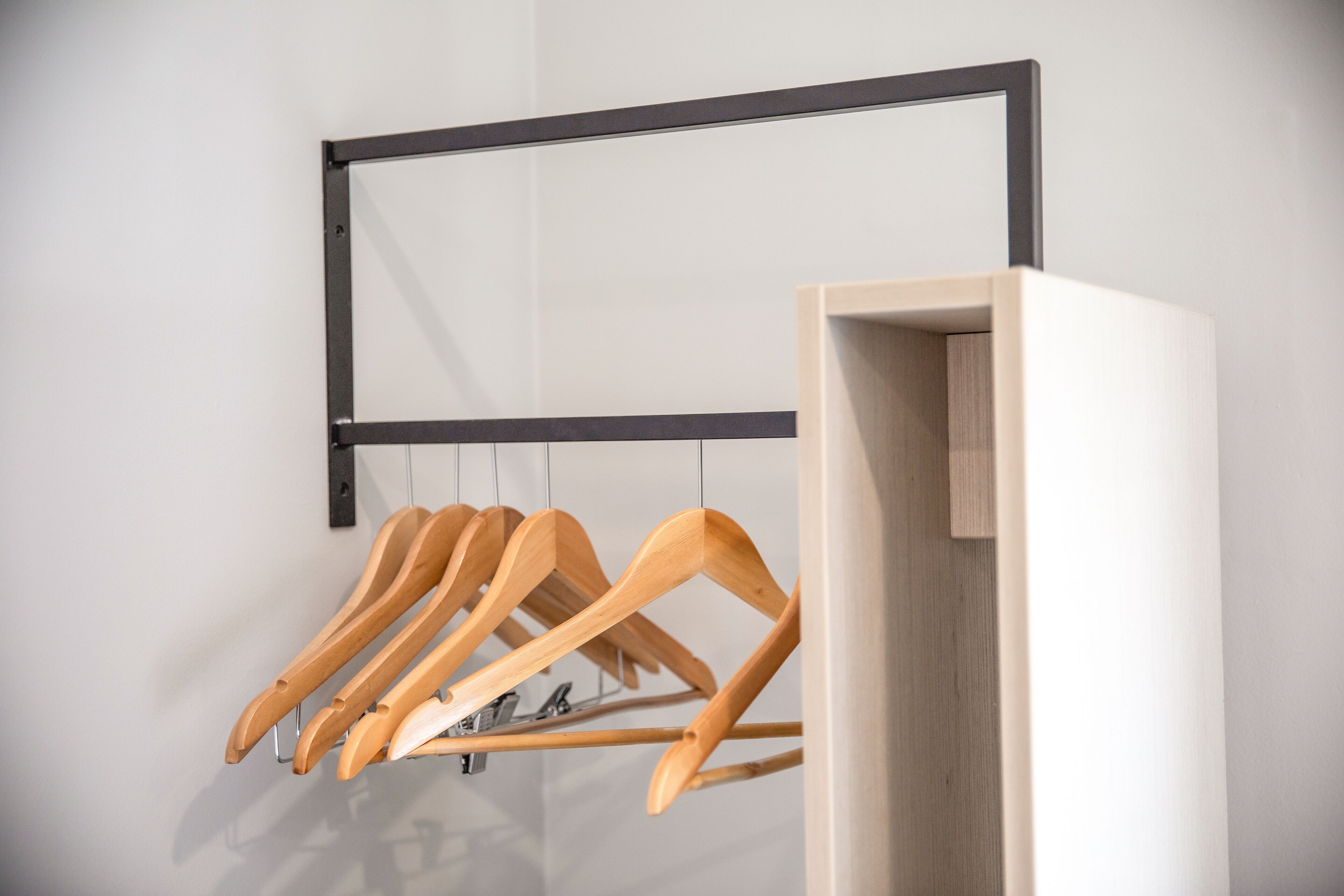 Un perchero de madera con varios ganchos frente a una pared blanca.