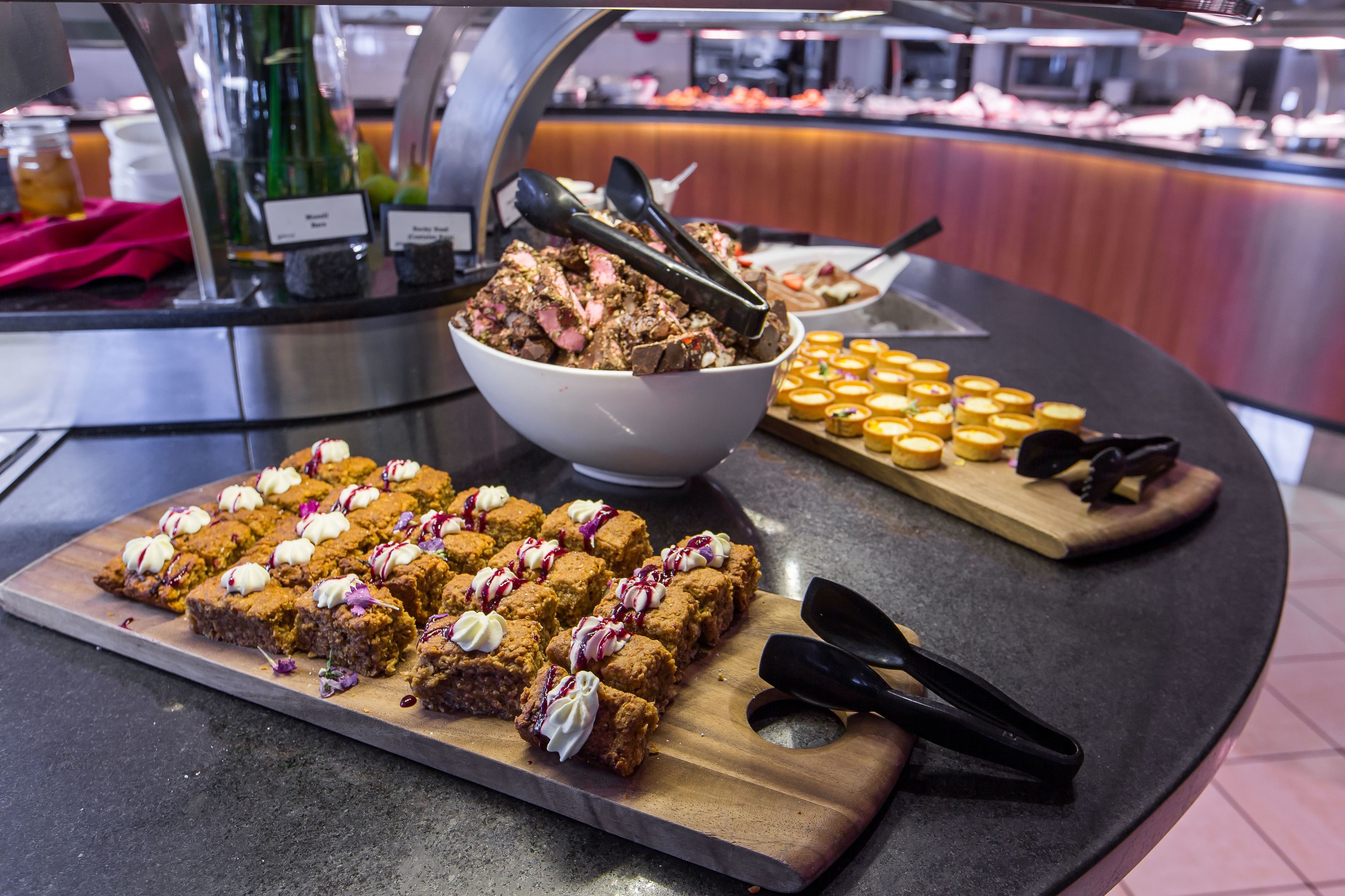 A buffet with various desserts, including brownies and mini cakes, on wooden serving boards.