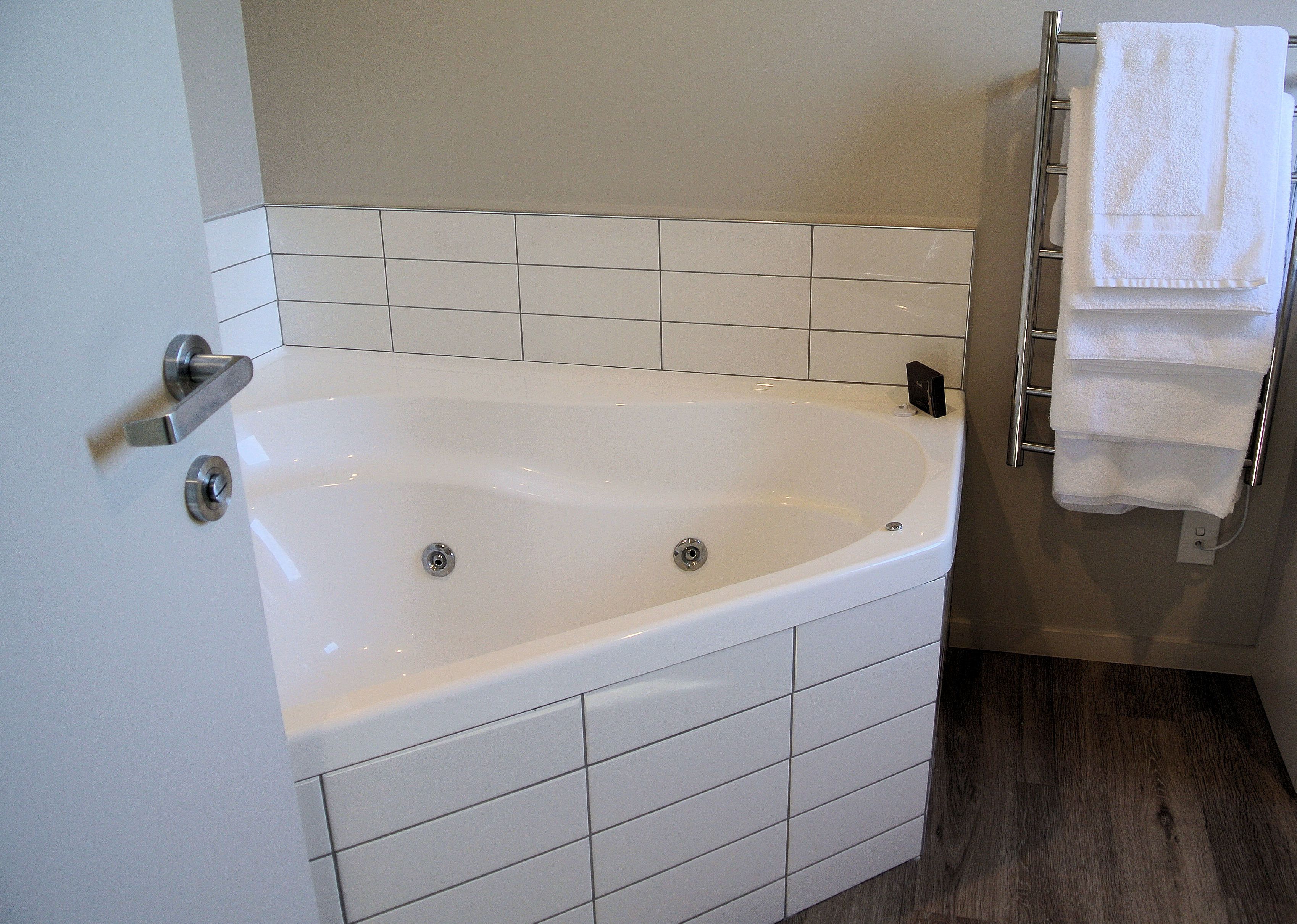 Un bagno con una vasca da bagno bianca, una parete rivestita in piastrelle e un portasciugamani.