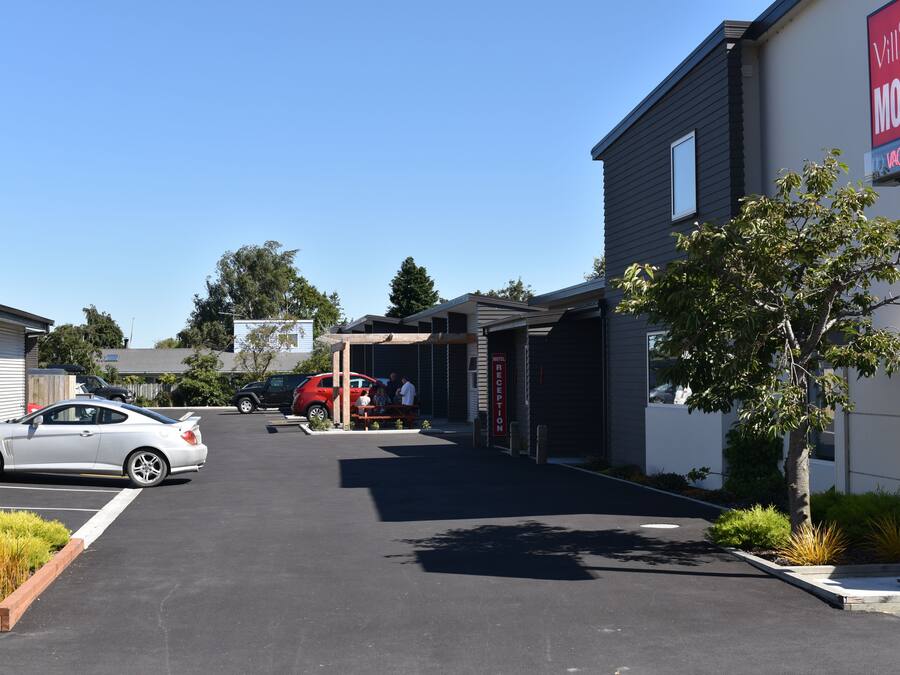A motel with a reception area, parked cars, and a clear sky.