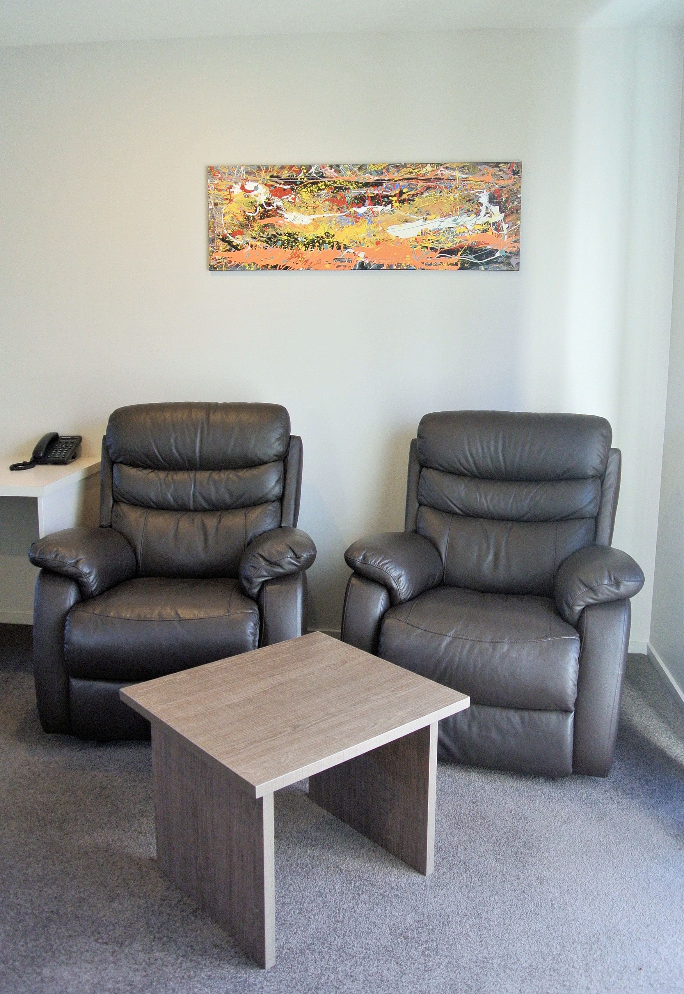 Two leather recliners, a small table, and a painting on the wall.