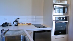 Een kleine keuken met een spoelbak, een koffiezetapparaat, een magnetron en een oven.