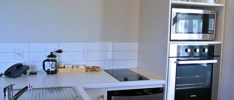 A compact kitchen with a sink, a coffee maker, a microwave, and an oven.