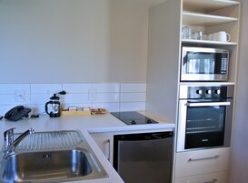 A compact kitchen with a sink, a coffee maker, a microwave, and an oven.