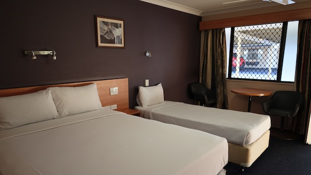 A hotel room with two beds, a small table, and a window with a view of the outside. - Sun Palms Motel (Allenstown)