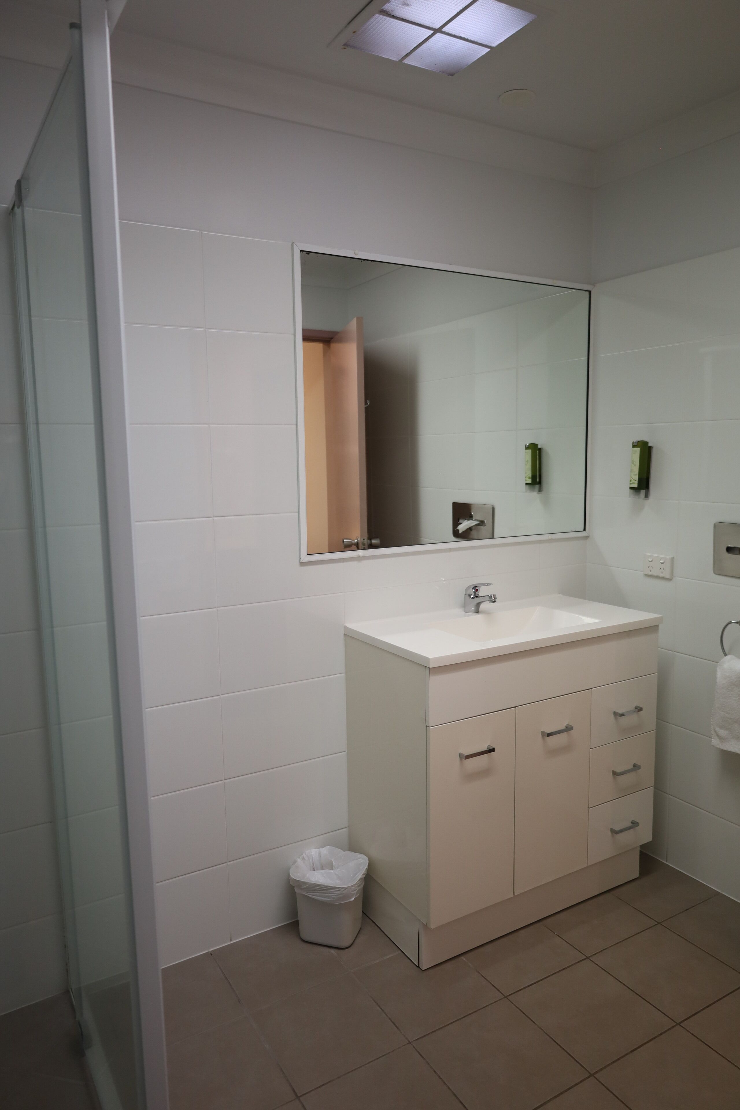 Un baño moderno con un lavamanos blanco, espejo y paredes con azulejos.
