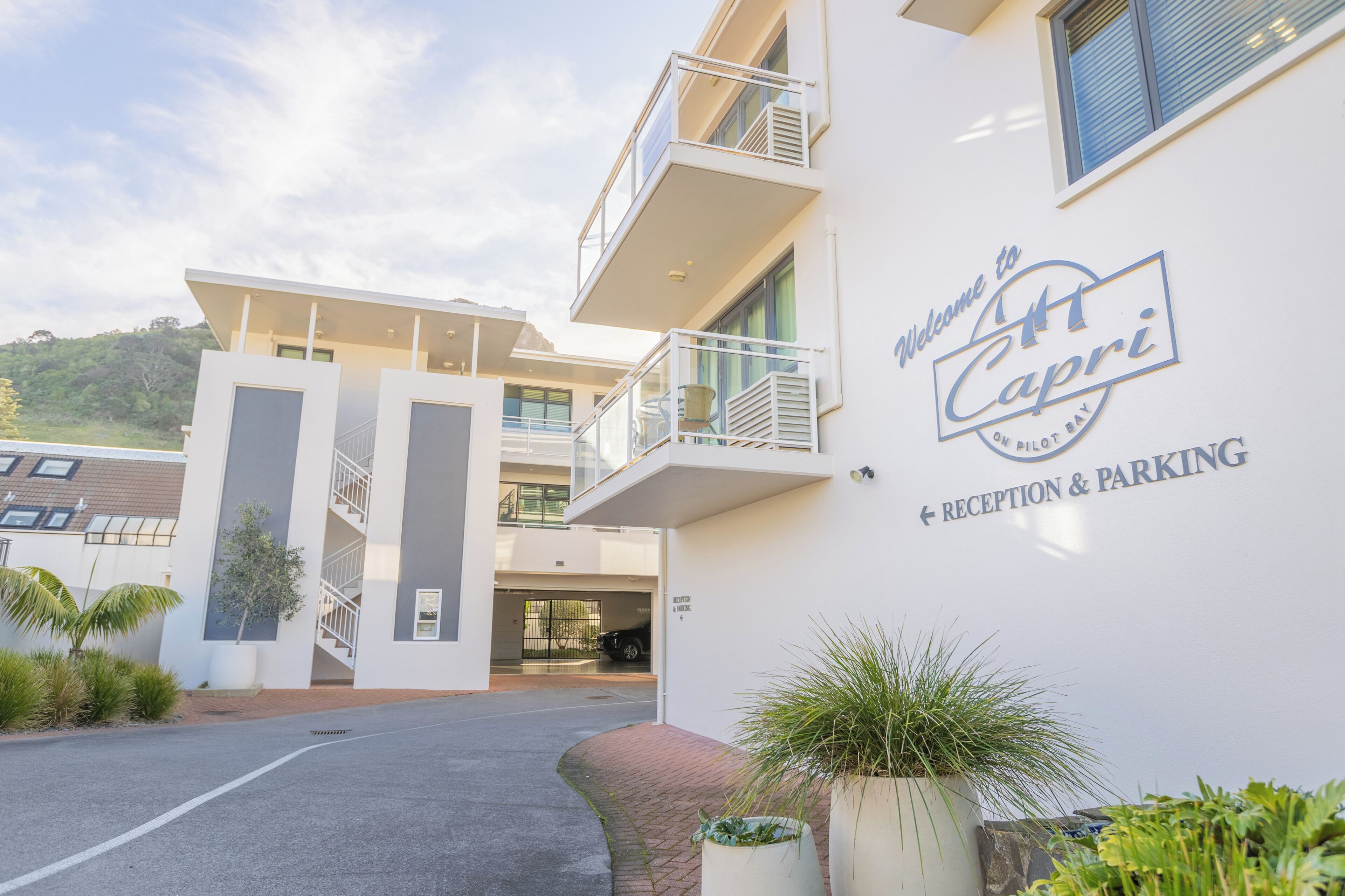 A modern building with a sign reading 'Welcome to St. Capri' indicating a reception and parking area.