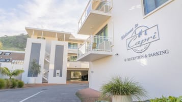 A modern building with a sign reading 'Welcome to St. Capri' indicating a reception and parking area.