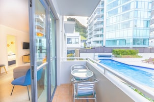 Habitación de hotel moderna con puerta de vidrio, una pequeña mesa y sillas, y vista a una piscina.