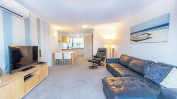 A modern living room with a leather sofa, a flat-screen TV, and a dining area with a table and chairs.