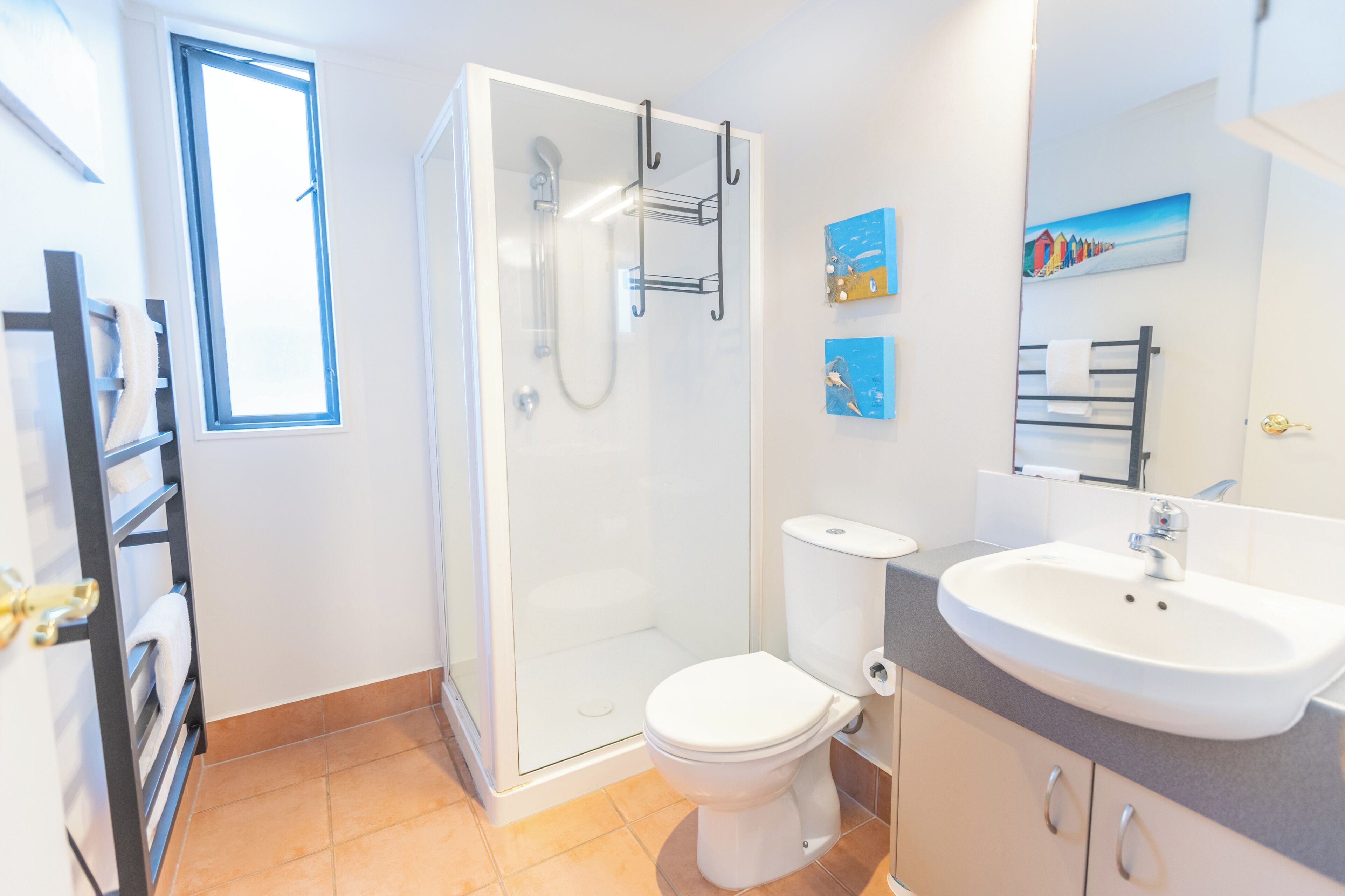 A modern bathroom with a glass shower enclosure, a toilet, a sink, and a towel rack.