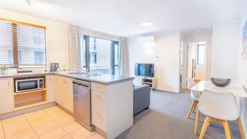A modern kitchen with a dishwasher, microwave, and a large window.